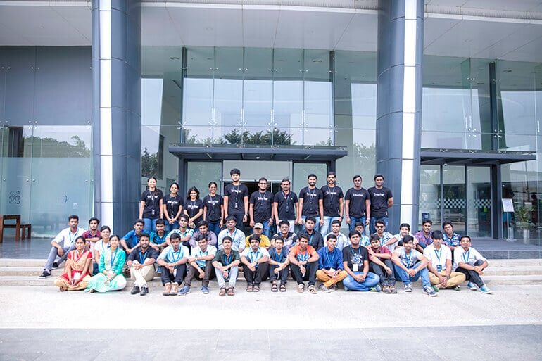 The Cliqtrix finalists seated on the steps outside a glass-fronted office building